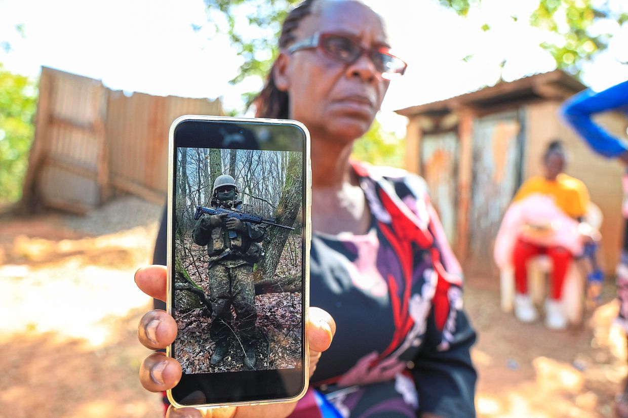 Bibiana Wangari, mother of Charles Waithaka, holding a phone showing a picture of him in Russia, during a memorial service for Charles.