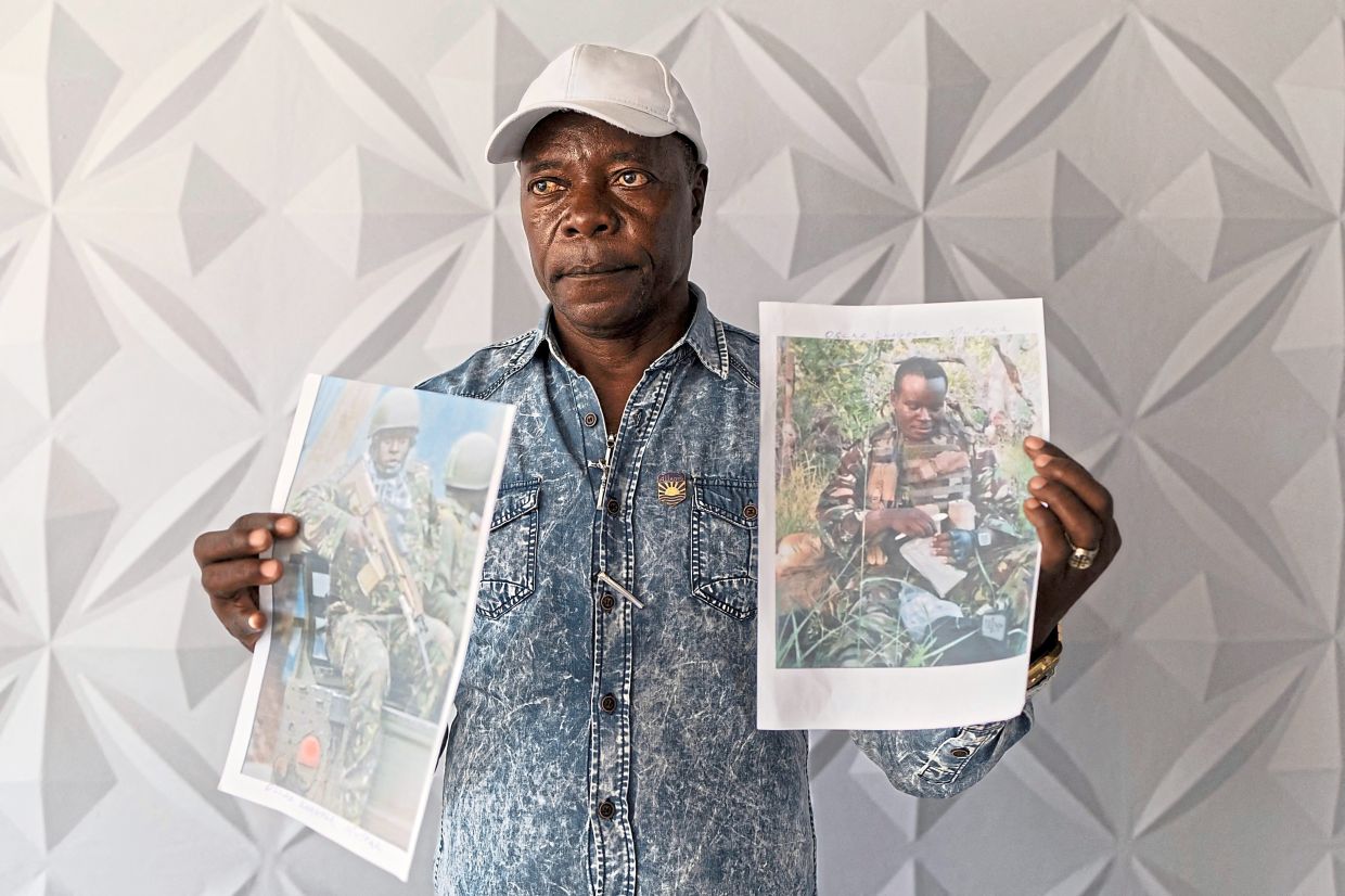 Charles Ojiambo Mutoka, posing with portraits of his son, Oscar, whom he learnt was killed in August. — AP/AFP