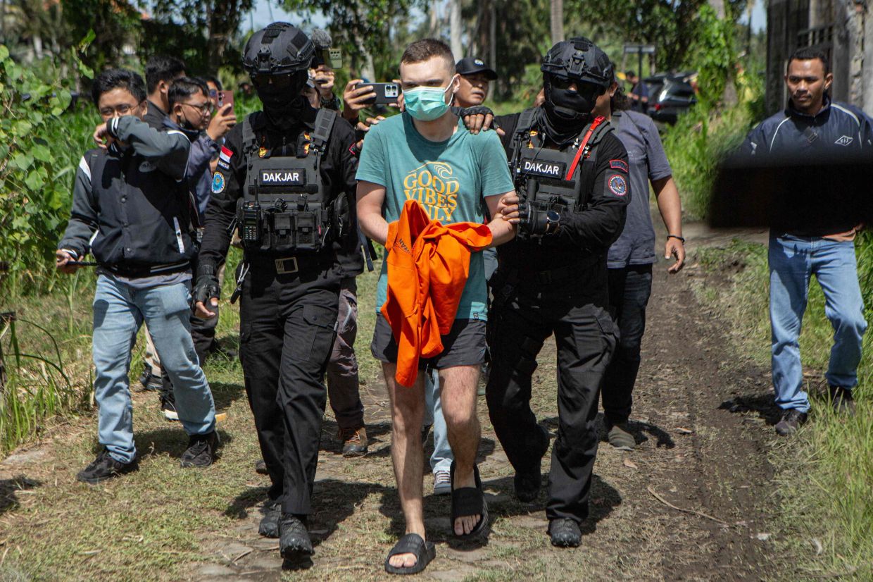Russian national suspectsS.T. (centre), 34, accused of operating a laboratory producing the synthetic drug mephedrone, is escorted by police to the house used to manufacture drugs during a crime scene reconstruction as authorities search for another foreign suspect in Gianyar, on Indonesia's resort island of Bali. -- Photo by LANA PRIATNA / AFP