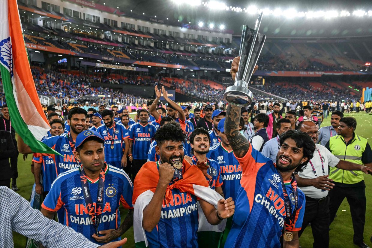 (from left to right) India's captain Suryakumar Yadav, Mohammed Siraj, Ishan Kishan, and Tilak Varma celebrate with the trophy during a victory lap after winning the 2026 ICC Men's T20 Cricket World Cup final match against New Zealand at the Narendra Modi Stadium in Ahmedabad on March 8, 2026. - Photo by Punit PARANJPE / AFP