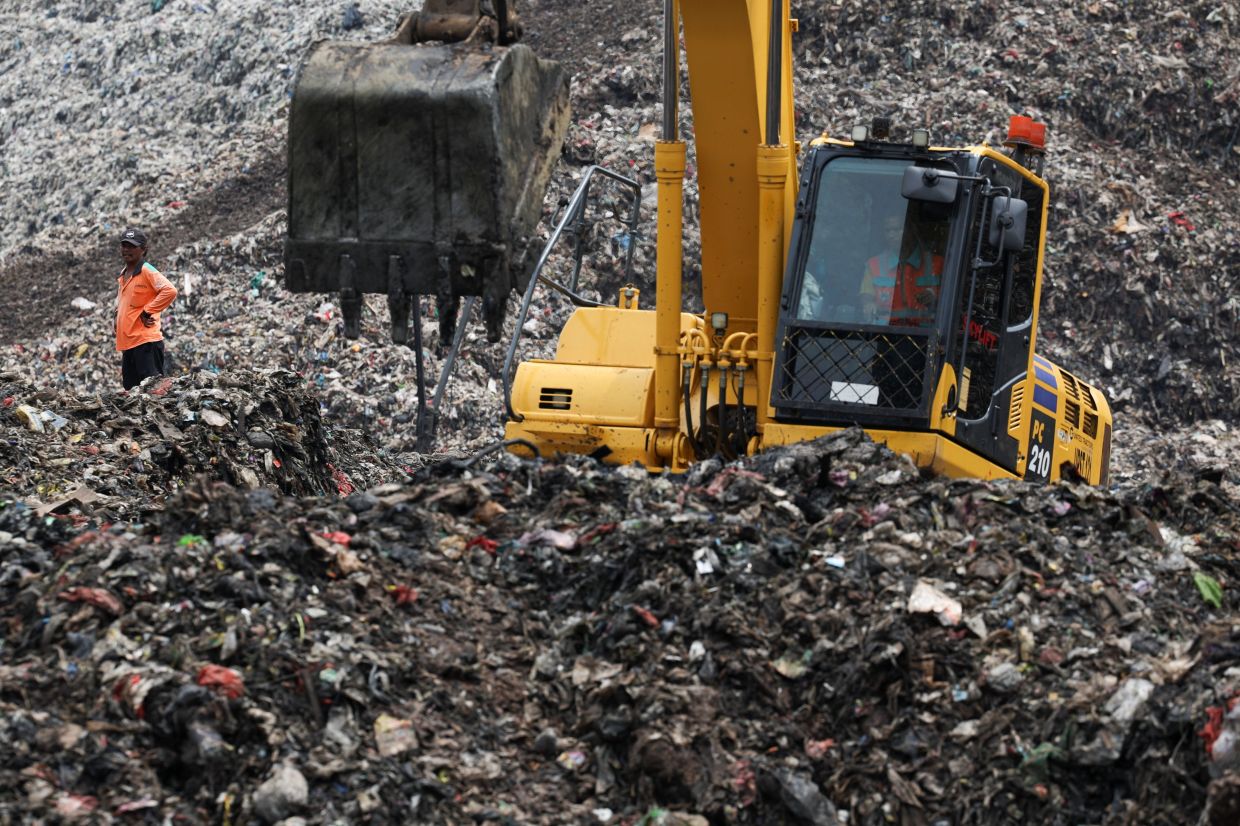 A worker stands amid garbage at the site of a collapse at the Bantar Gebang landfill, while an excavator operates during a rescue operation in Bekasi, on the outskirts of Jakarta, Indonesia, on Monday, March 9, 2026. -- Photo: REUTERS/Ajeng Dinar Ulfiana