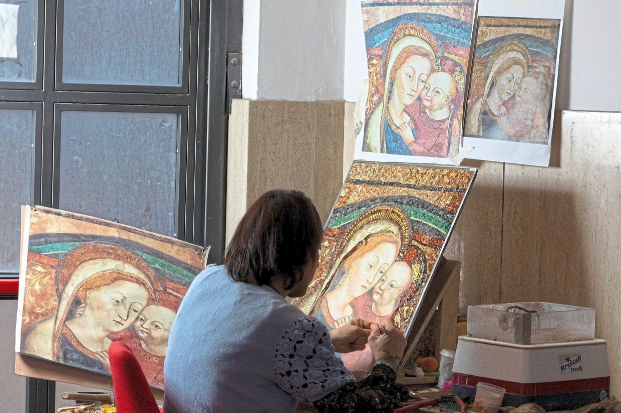 A worker crafting a new mosaic inside the Vatican Mosaic Studio. — Reuters 