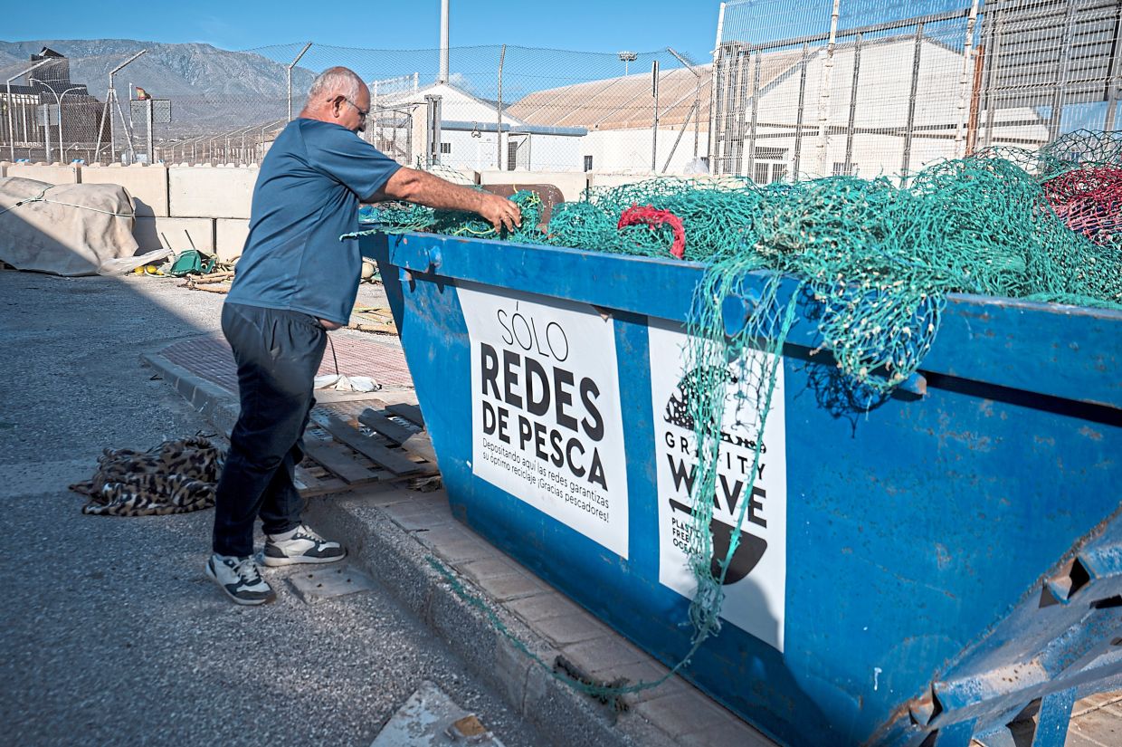 A man drops old fishing nets that will be recycled.