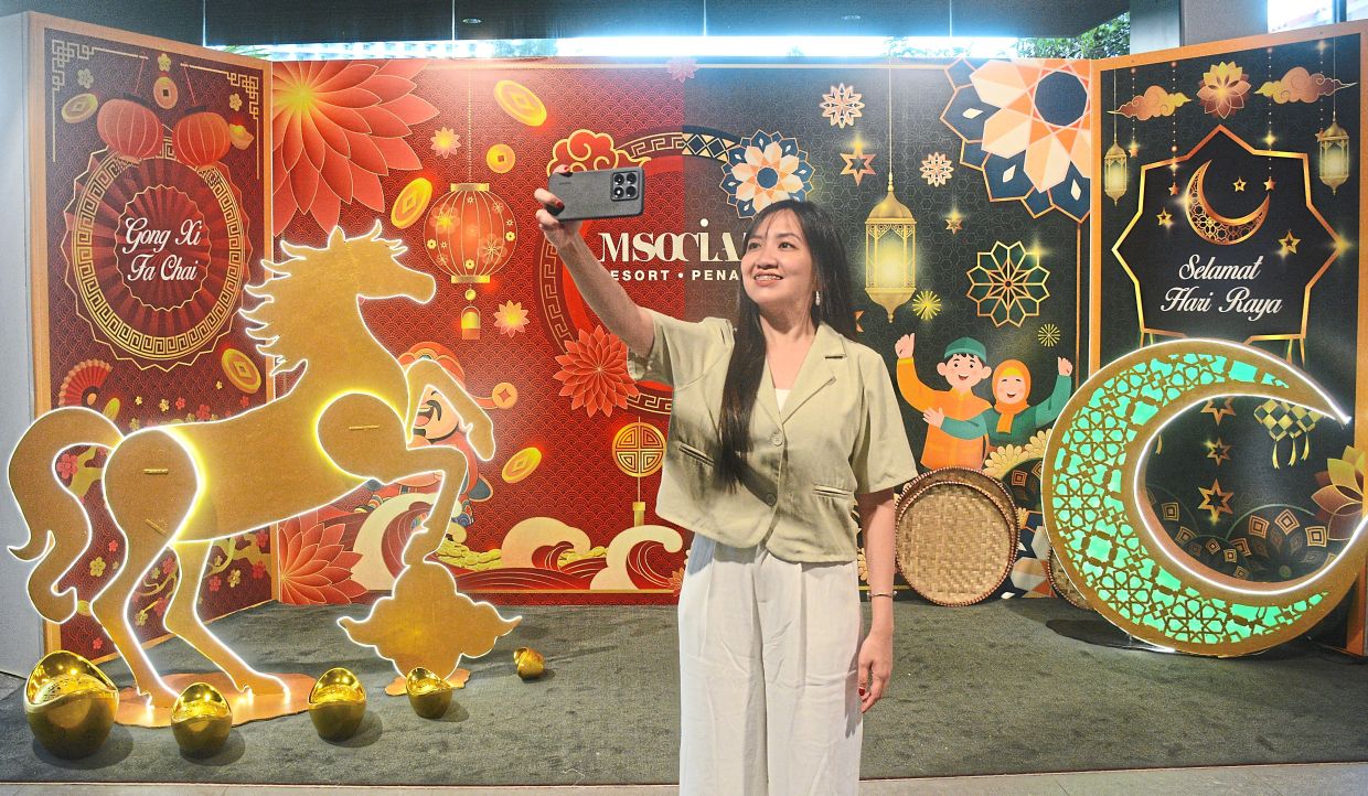 A visitor to M Social Resort Penang taking photos with the backdrop depicting Chinese New Year and Hari Raya decorations.