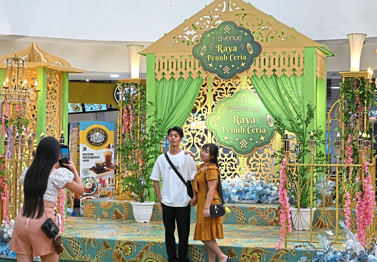 Visitors taking photos in front of 1st Avenue Penang’s green and gold backdrop.