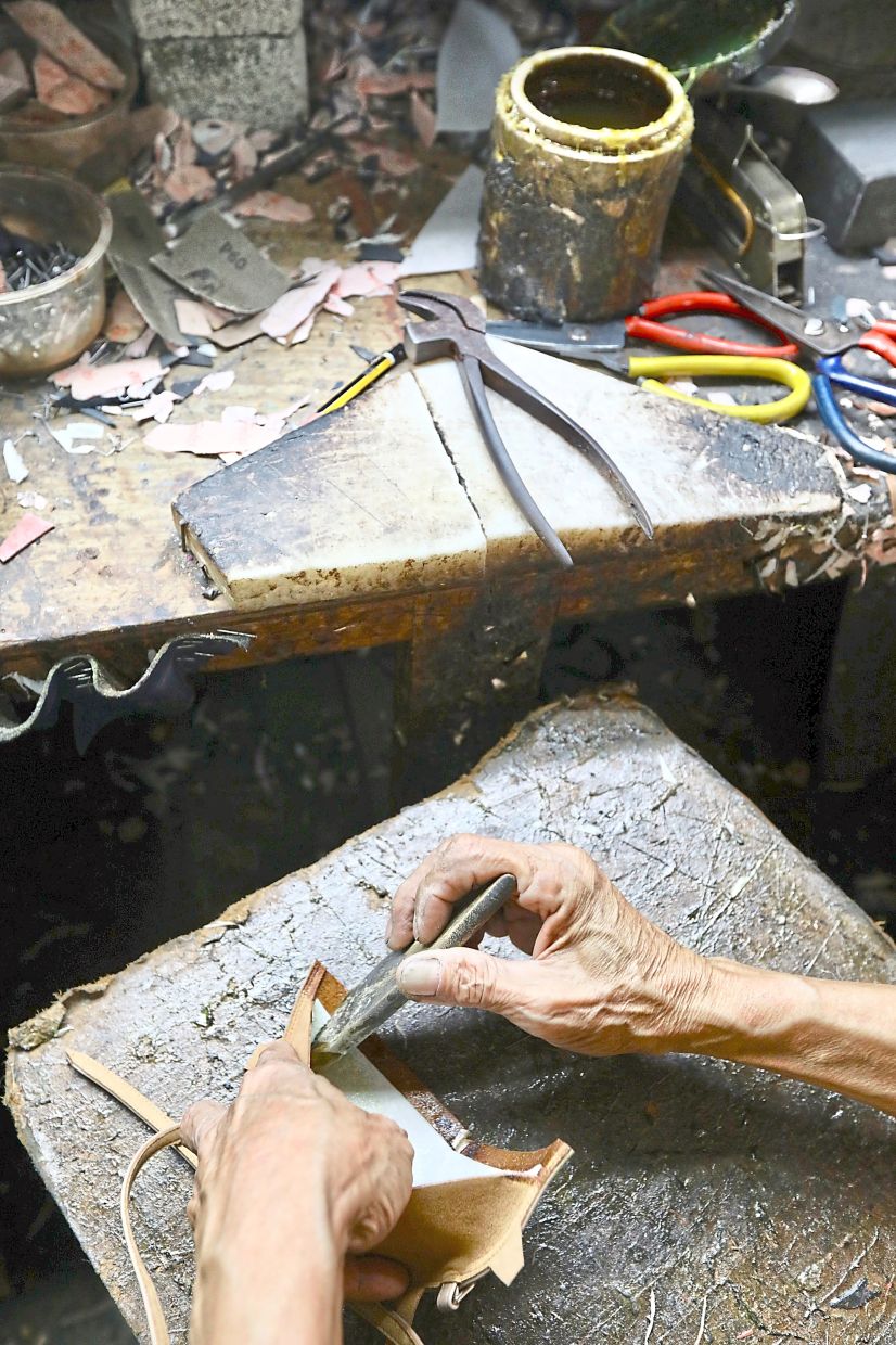 Chin diligently working on the soles of the shoes, not an east task but one he enjoys even after all this time.