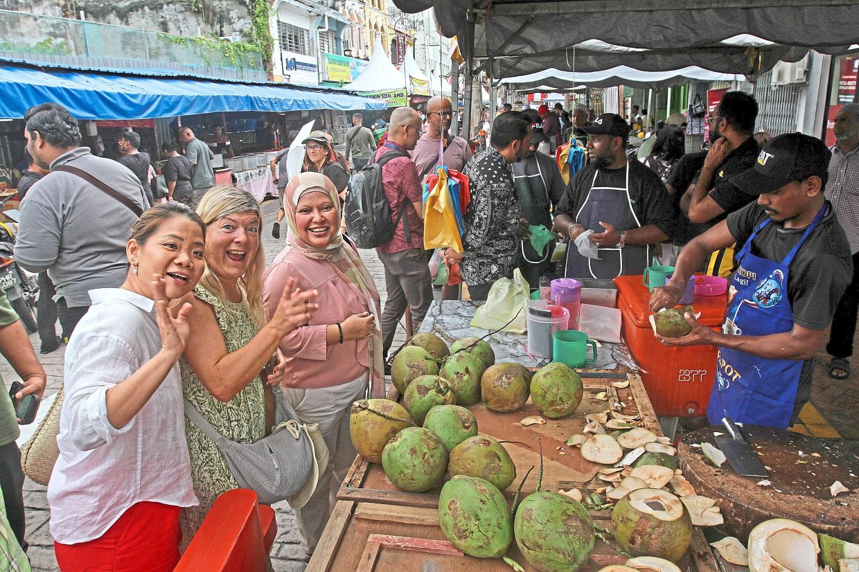 Getting some thirst quenchers are three visitors awaiting fresh coconut water at Ramadan Food Fest ’26 in Lebuh Queen, George Town (above), and bazaar visitors lining up for ‘air balang’ which include mango, cocoa and Thai tea drinks in Kota Damansara (left).