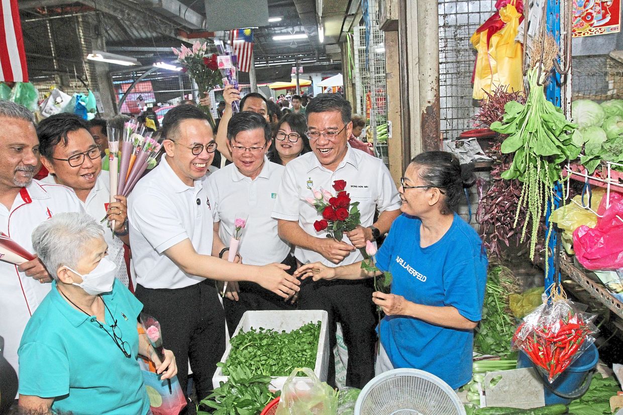 (From left in white shirts) Ramkarpal, Ng, Sim, Chow and Wong giving away flowers at Air Itam market for International Women’s Day. — Photos: LIM BENG TATT/The Star