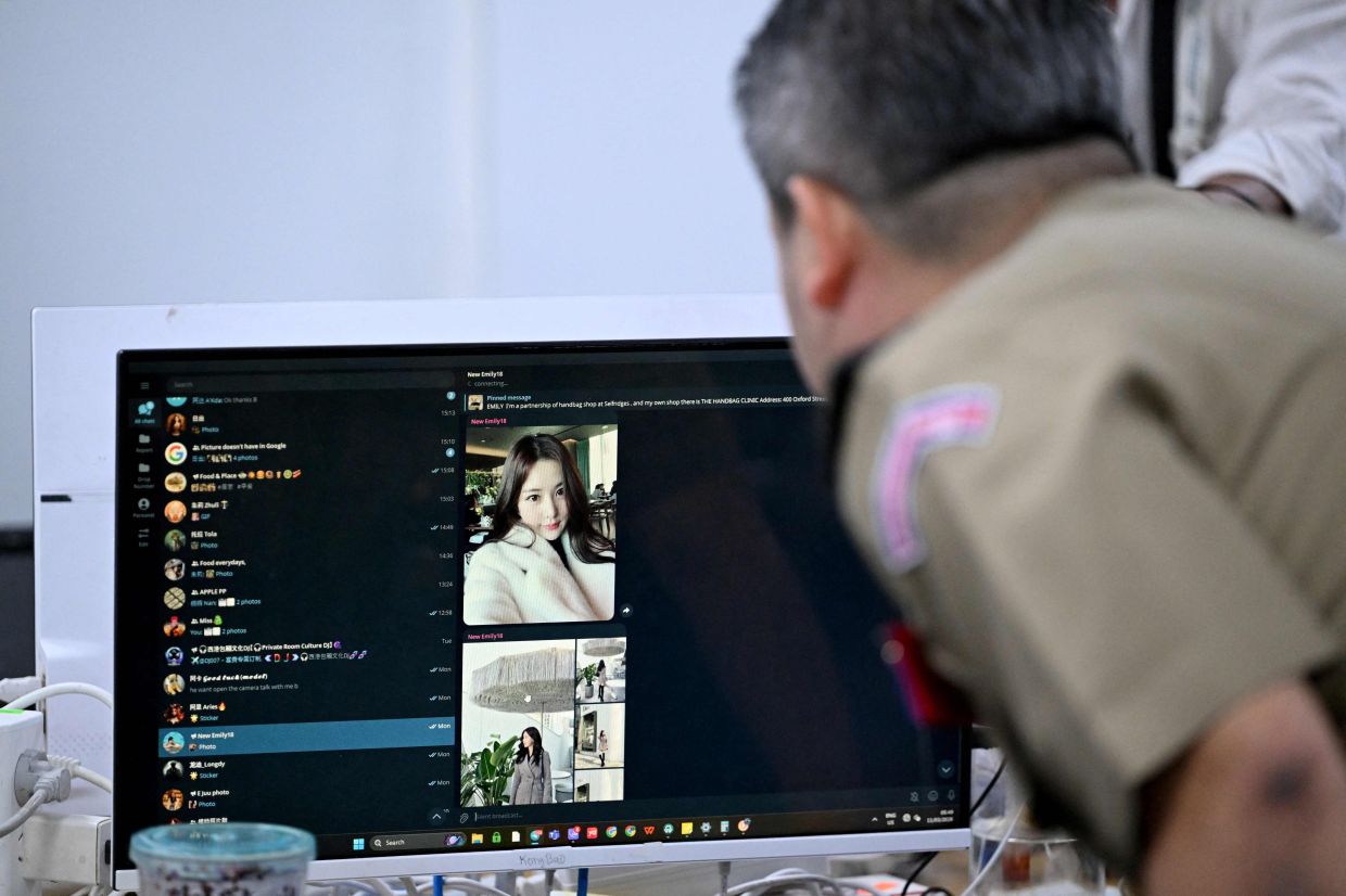 Major General Bun Sosekha, deputy commissioner in charge of the Security Unit Commissariat of Phnom Penh, looks at a seized monitor at a cyberscam operation centre following a raid the night before in Phnom Penh on March 11, 2026. — AFP