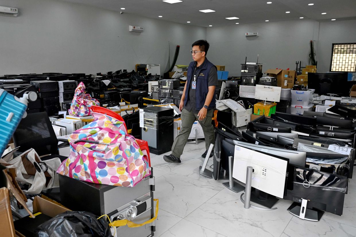 A police officer walks next to seized equipment confiscated from cyberscam operation centres at the Commissariat of Phnom Penh Municipal Police in Phnom Penh on March 11, 2026. — AFP
