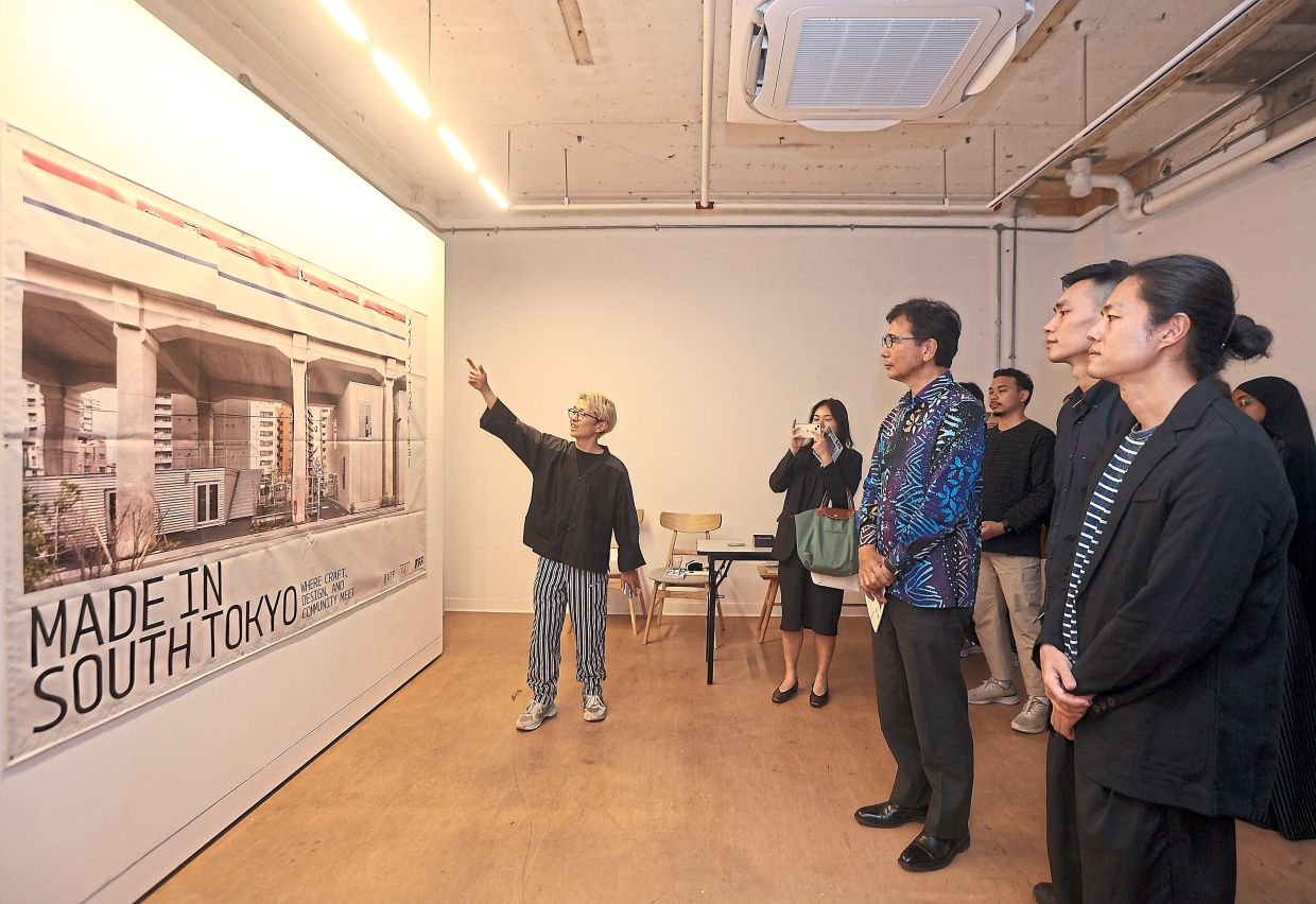 Muraji (left) giving guests, including (from right) Lim, Tan and Noriyuki, a tour of the exhibition.