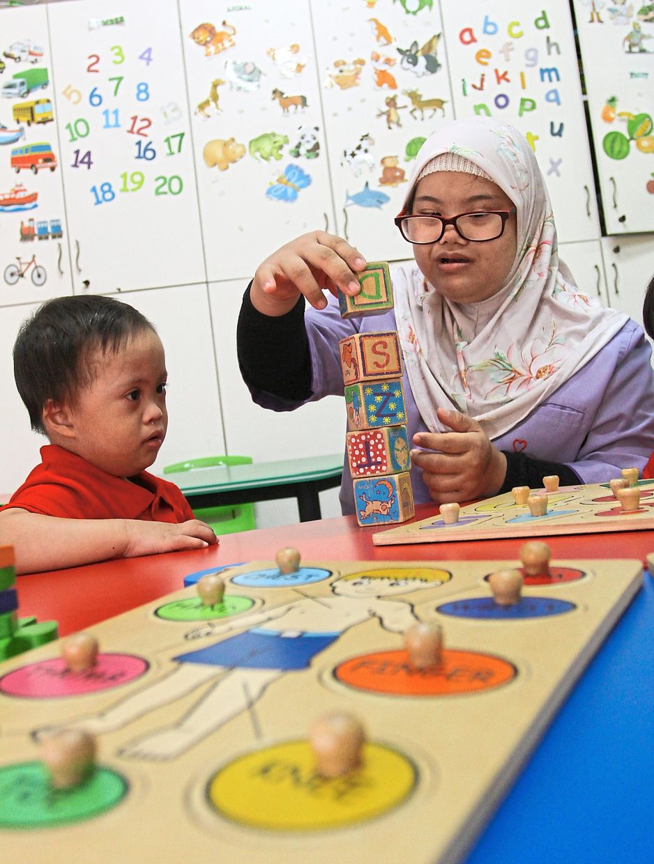 Wan Alya works as an assistant carer at a preschool for children with Down Syndrome. Photo: Filepic