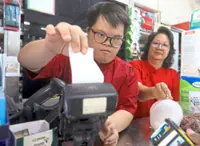 Malaysian young adult with Down syndrome handles cashier duties with confidence
