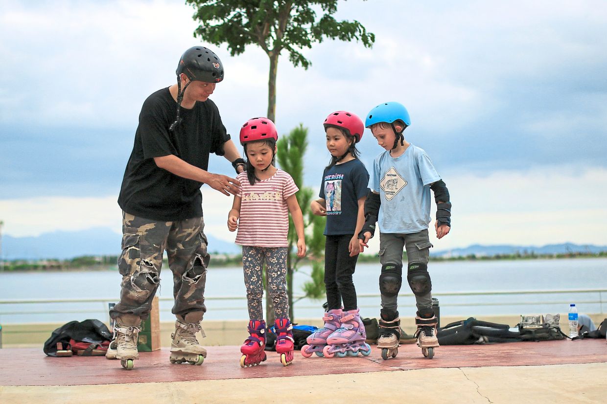 A senior inline skater guiding younger skaters to take their first steps towards a roll.