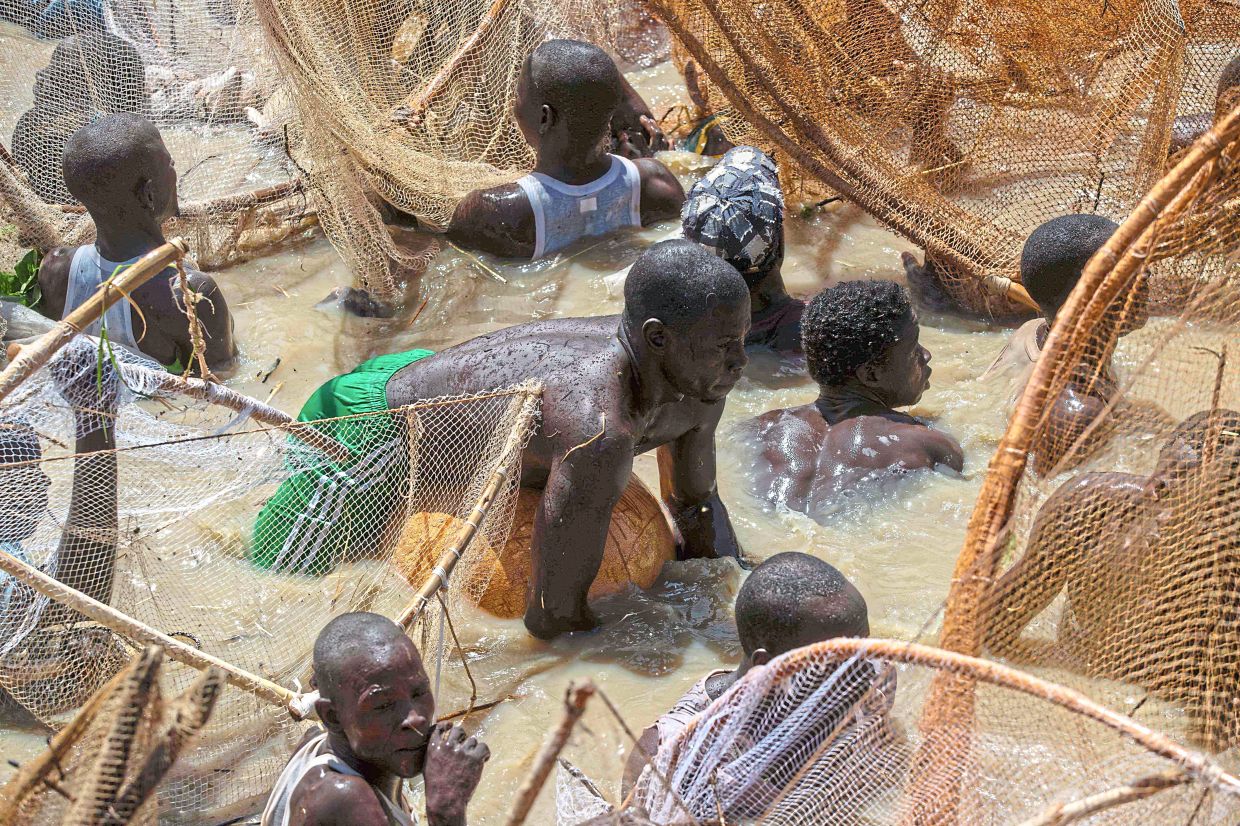 A fisherman floating on top of a calabash as other fishermen attempt to catch fish during the Argungu fishing festival. — AFP