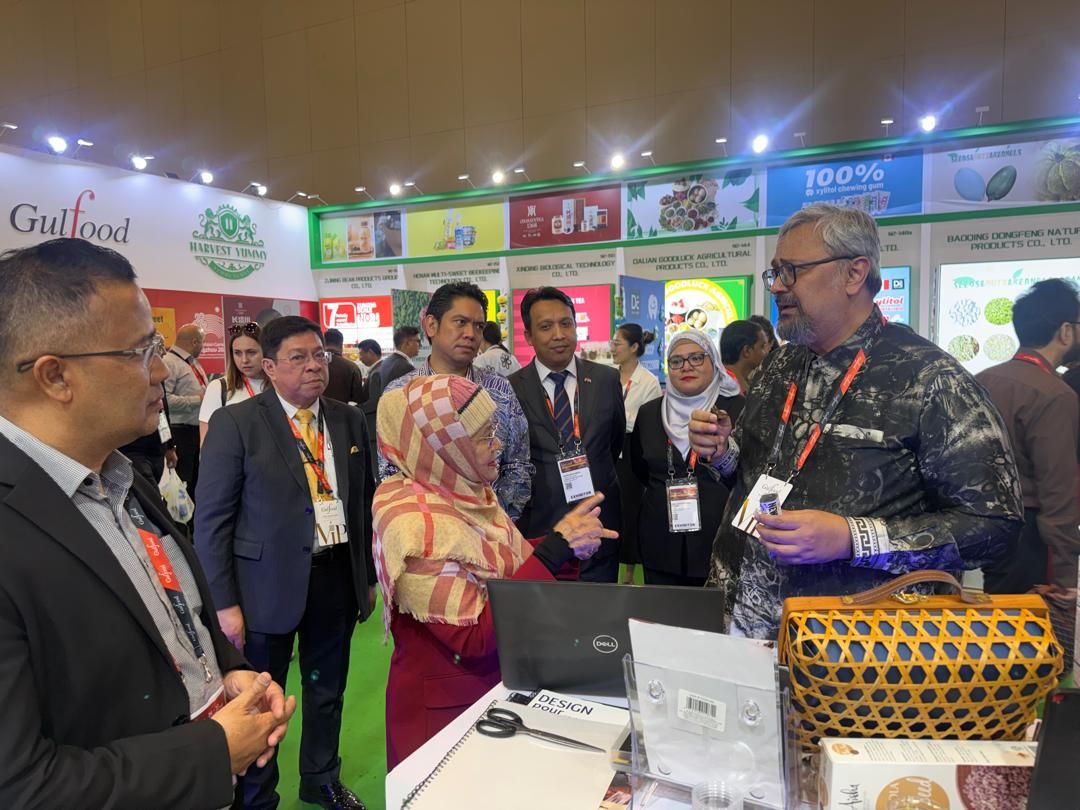 Tengku Datuk Sirajuzzaman (right) engages with Dr Aishah Solution Sdn Bhd founder Aishah Tul Radziah after officiating the Malaysian Pavilion at Gulfood 2026. Looking on are Idzham, Riaz, Matrade exports promotion and market access division manager Nurul Huda Kamarul Baharin, and other officials.