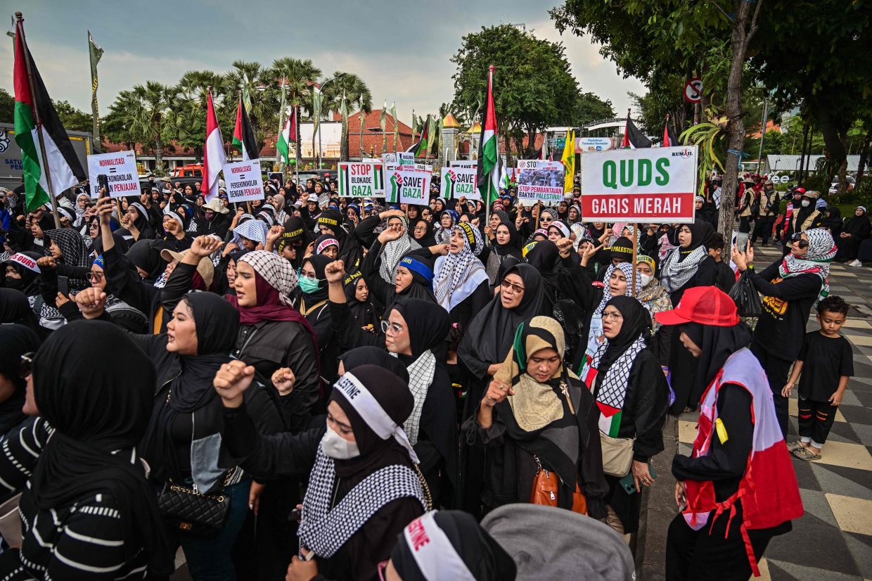 People hold placards and Palestinian flags during a demonstration to mark al-Quds (Jerusalem) Day, after Friday prayers in Surabaya on Friday, March 13, 2026. -- Photo by Juni KRISWANTO / AFP
