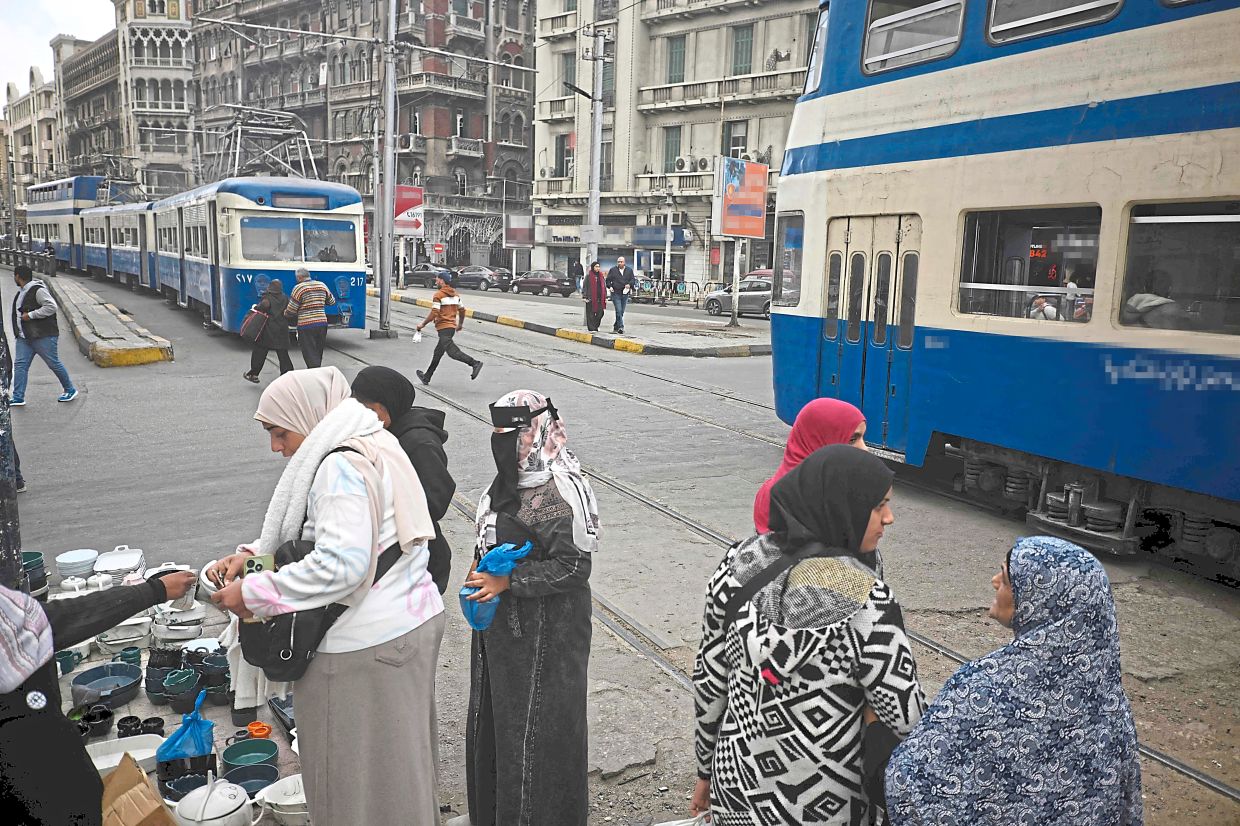 Women shopping at a stall set up near the tram line, one of the oldest means of transport which is earmarked for renovation, in Alexandria. — AFP