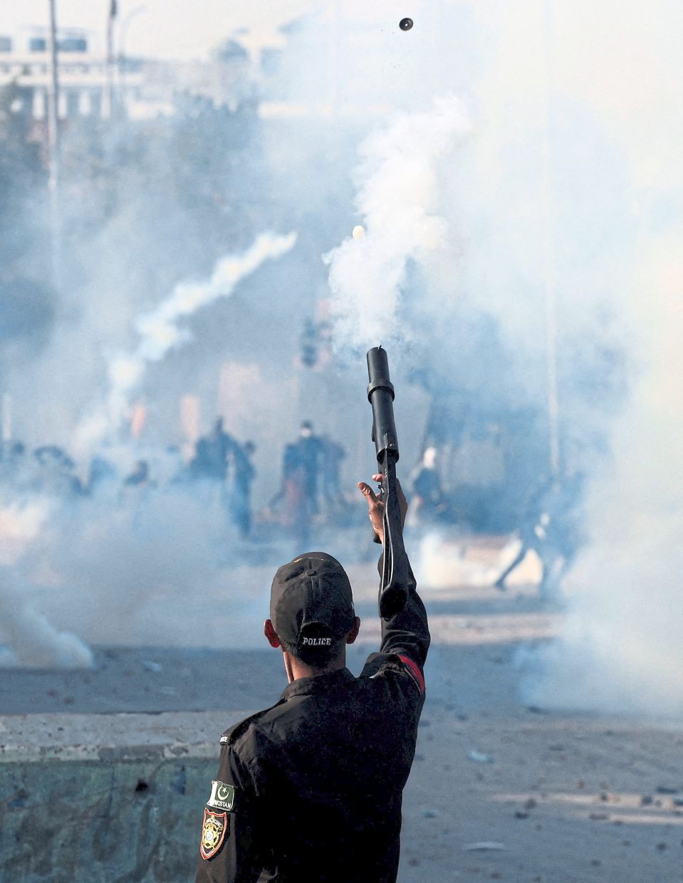 A police officer firing teargas to disperse protesters outside the US consulate-general in Karachi following US and Israeli strikes on Iran. — Reuters