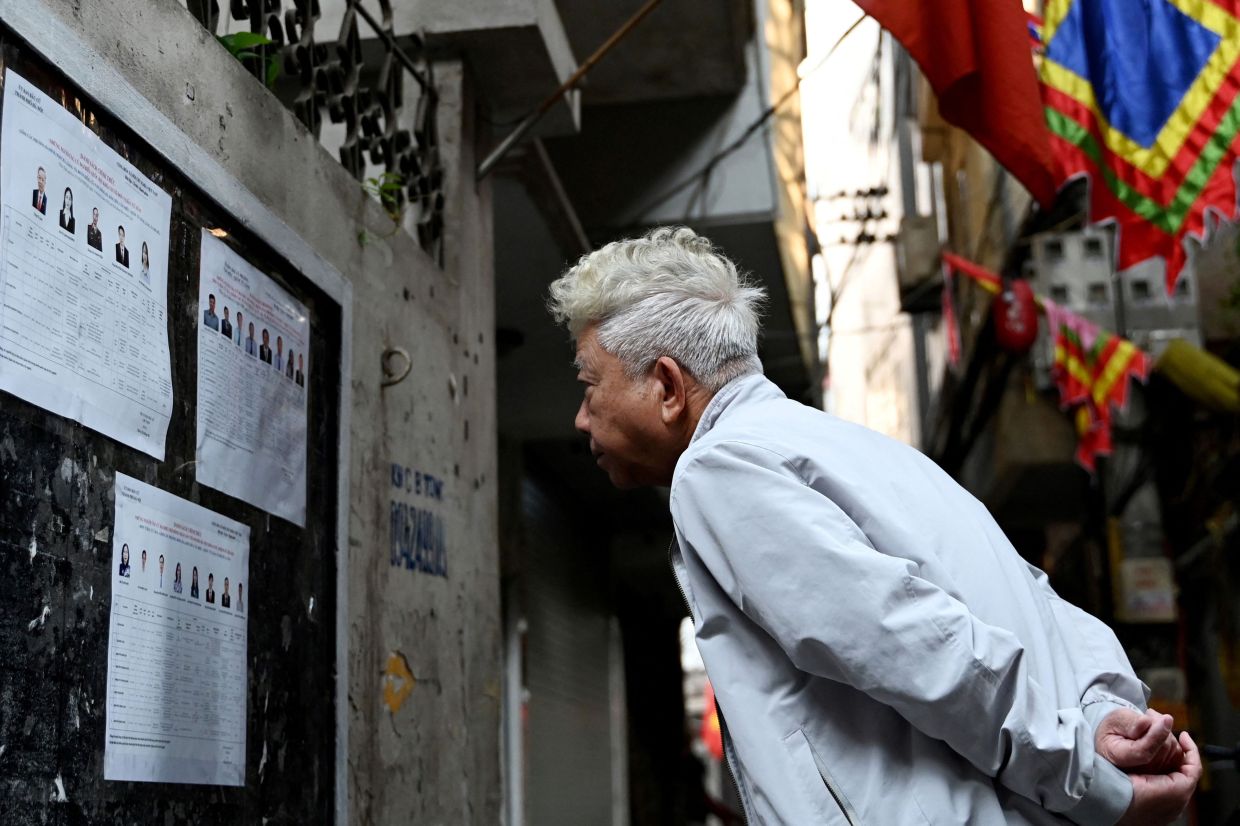 A man views the list of candidates for the upcoming National Assembly and local People's Council elections in a residential area in Hanoi on March 13, 2026. Vietnam goes to the polls on Sunday, March 15 to elect members of the National Assembly, the country's top legislative body that serves mainly to ratify decisions by the ruling Communist Party. -- Photo by Nhac NGUYEN / AFP