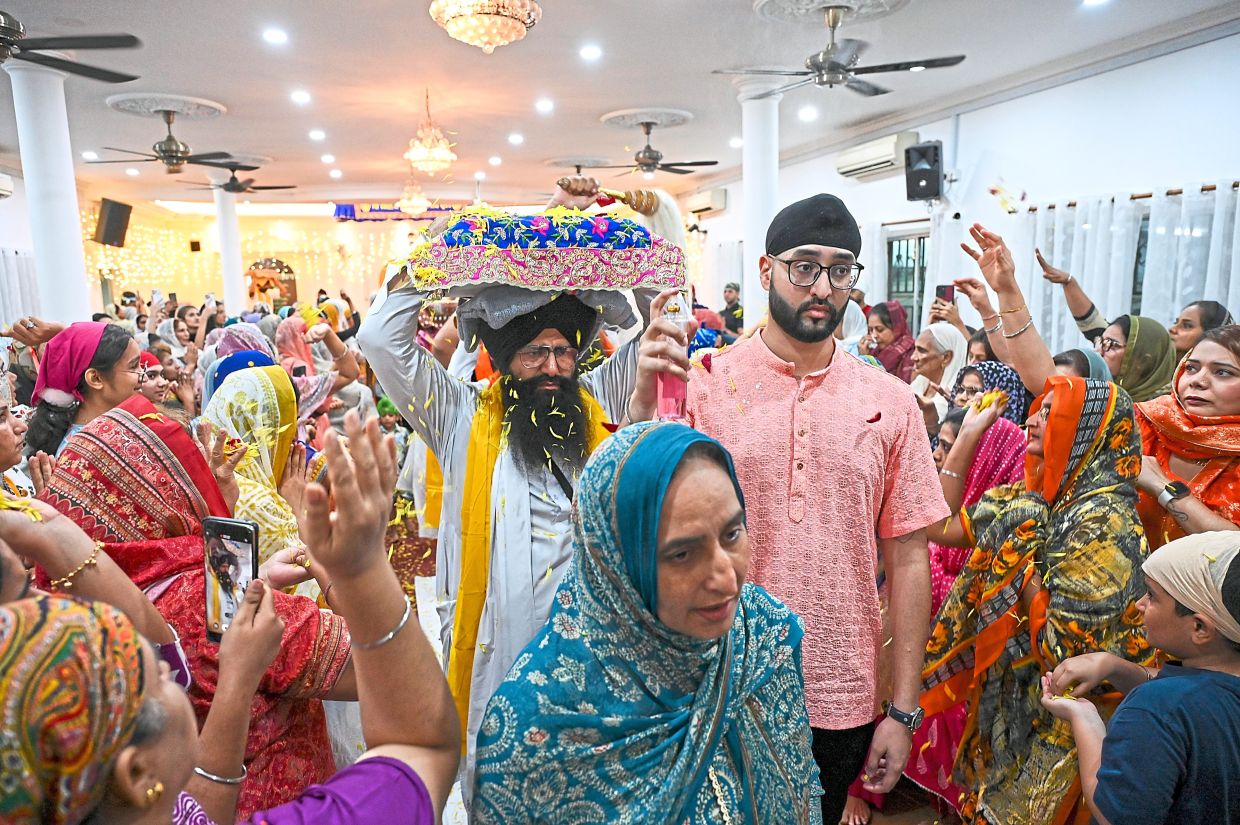 Giani Manpreet Singh carrying SGGS for relocation on Gurdwara Sahib Petaling Tin’s last day with devotees showering its path with flower petals. — Photos: IZZRAFIQ ALIAS/The Star 
