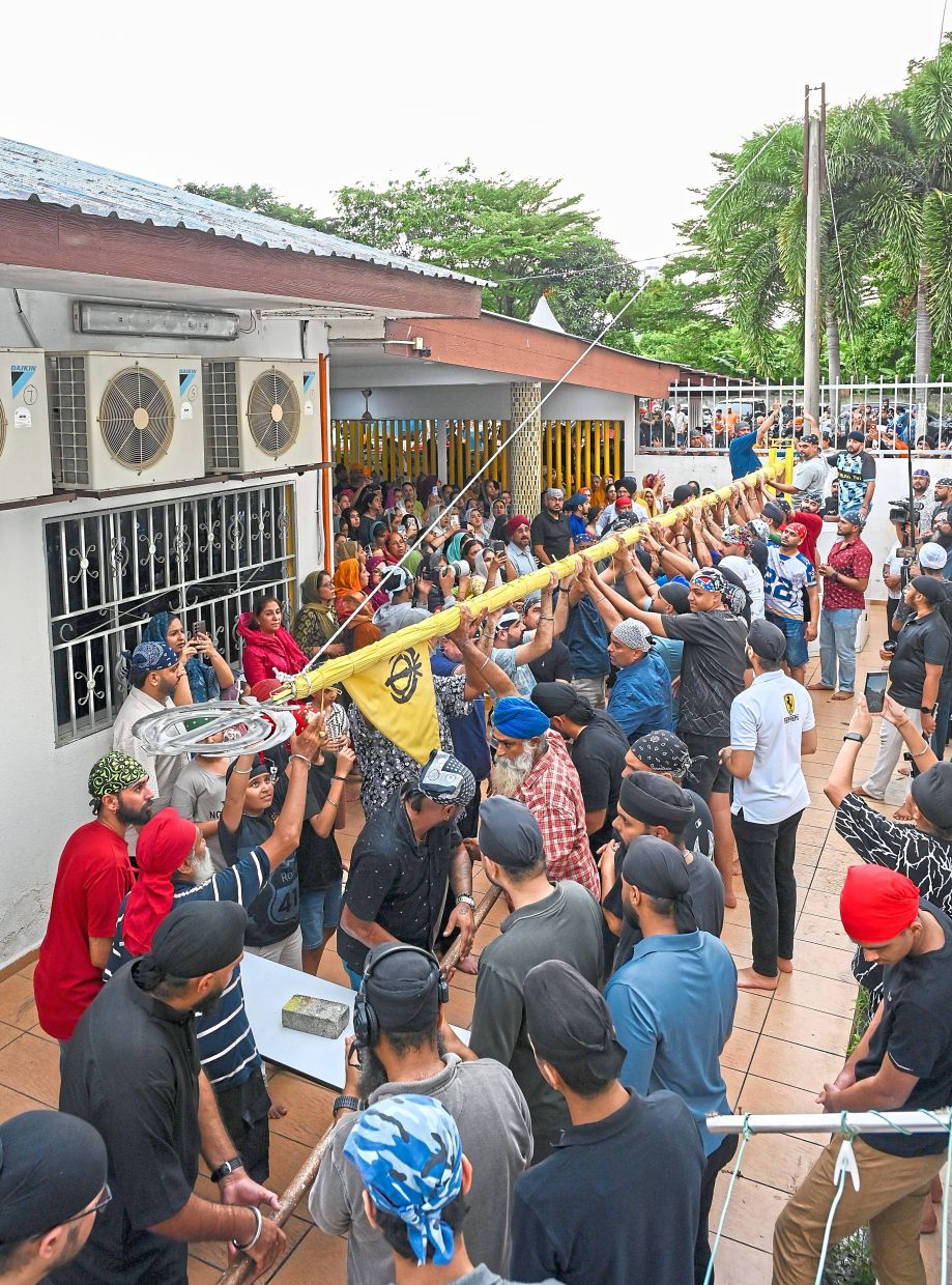 Volunteers helping to lower the Sikh flag and flagpole before the temple’s closure. 