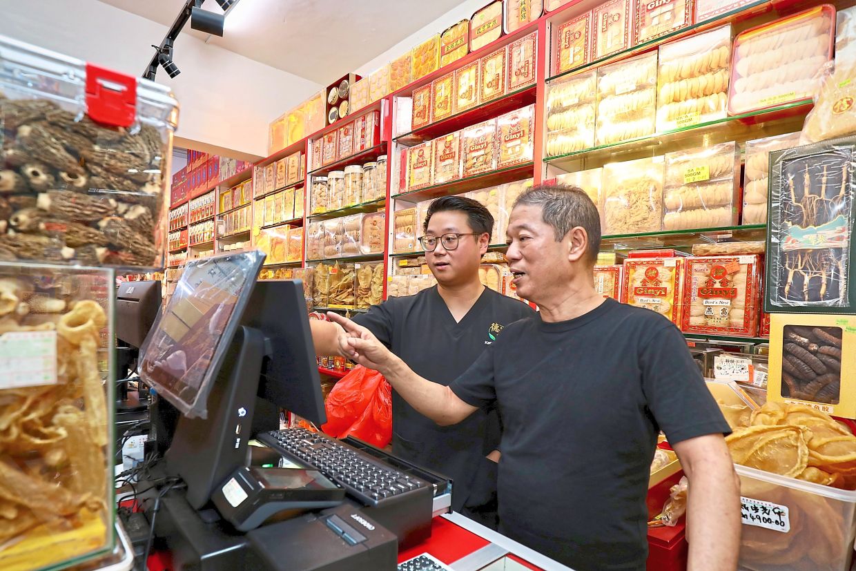 Kenneth helping father Chee Khai with digitising invoices at their shop in Petaling Jaya.