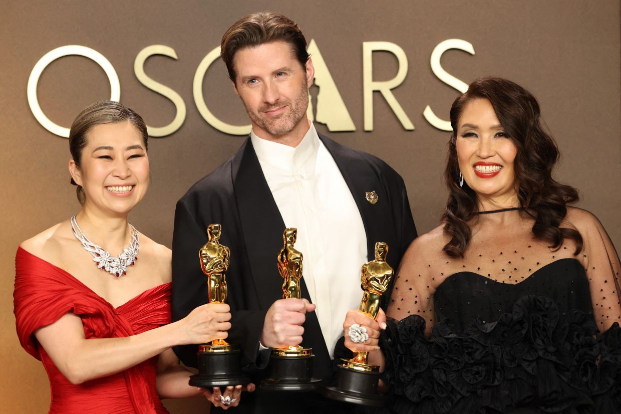 (From left) Maggie Kang, Chris Appelhans and Michelle L.M. Wong pose with the Oscar for Best Animated Feature Film for 'KPop Demon Hunters'. Photo: Reuters