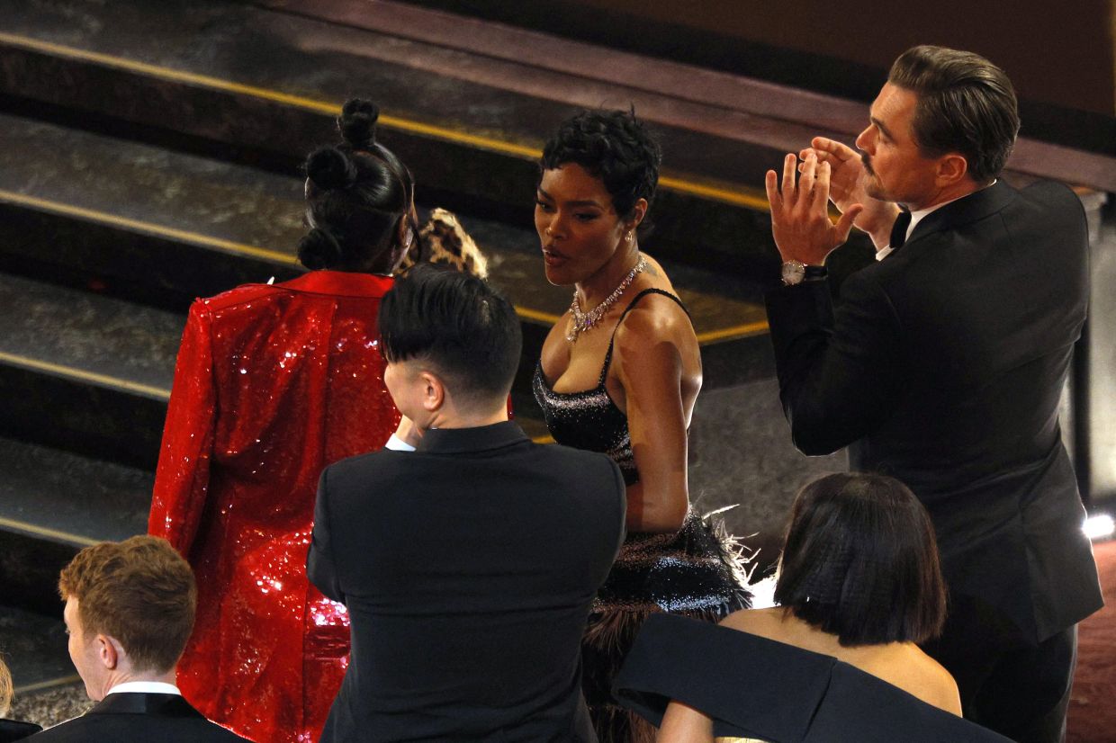 Leonardo DiCaprio and Teyana Taylor applaud as Paul Thomas Anderson wins the Oscar for Best Adapted Screenplay for 'One Battle After Another'. Photo: Reuters