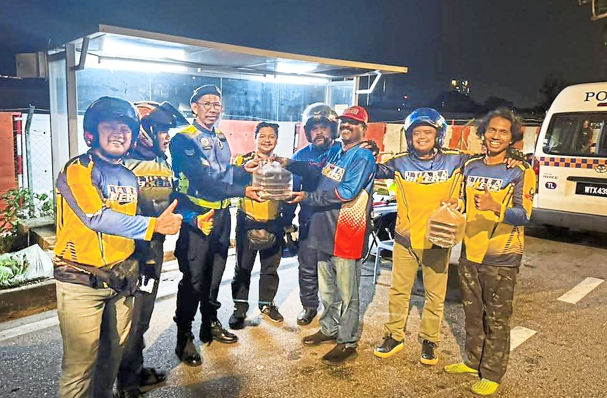 Mohd Jahubar (third from right) and Utara Bikers members distributing food packets to policemen manning a roadblock at USM.