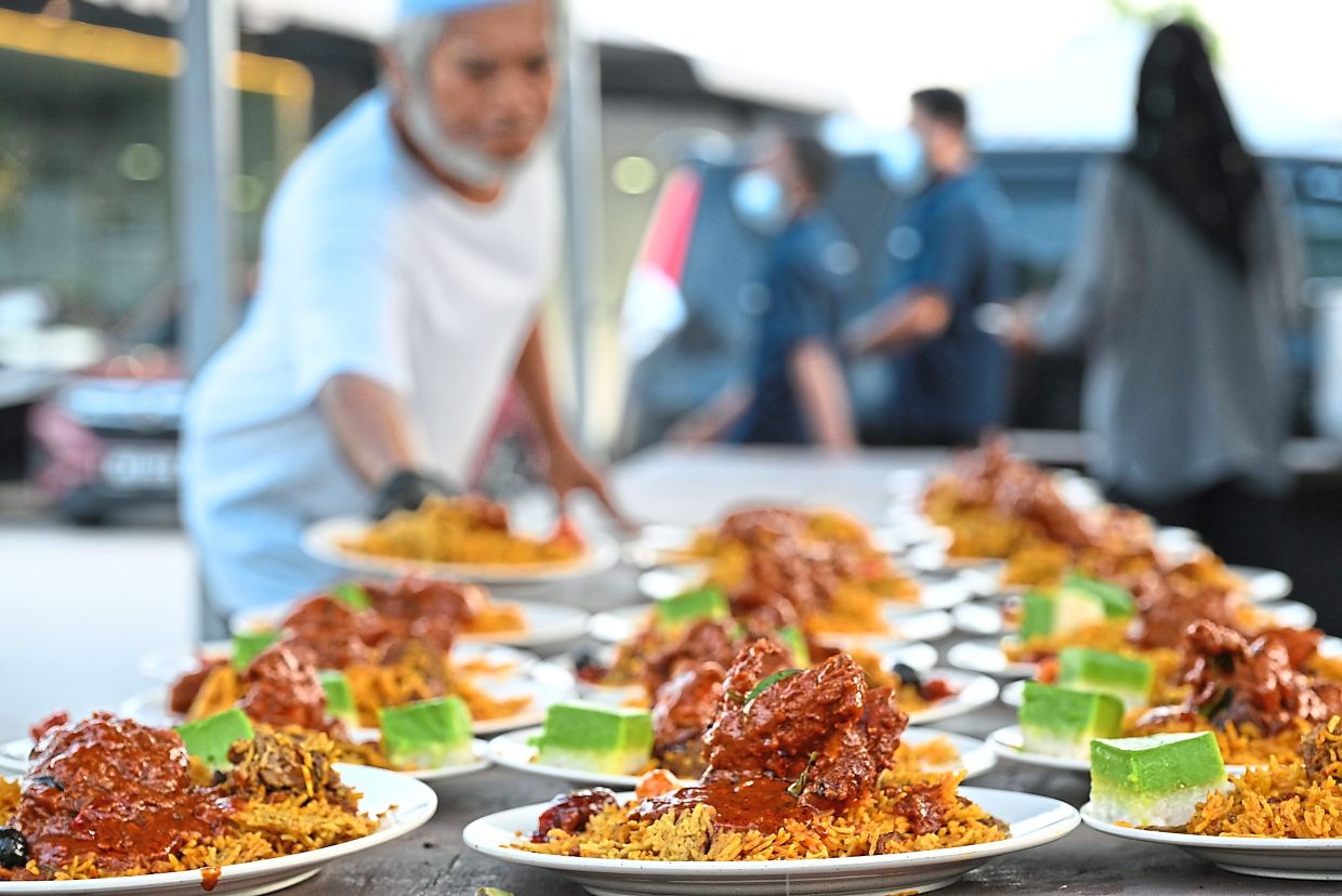 Mosque volunteers serving up beef briyani for breaking fast. — Photos: KT GOH/The Star