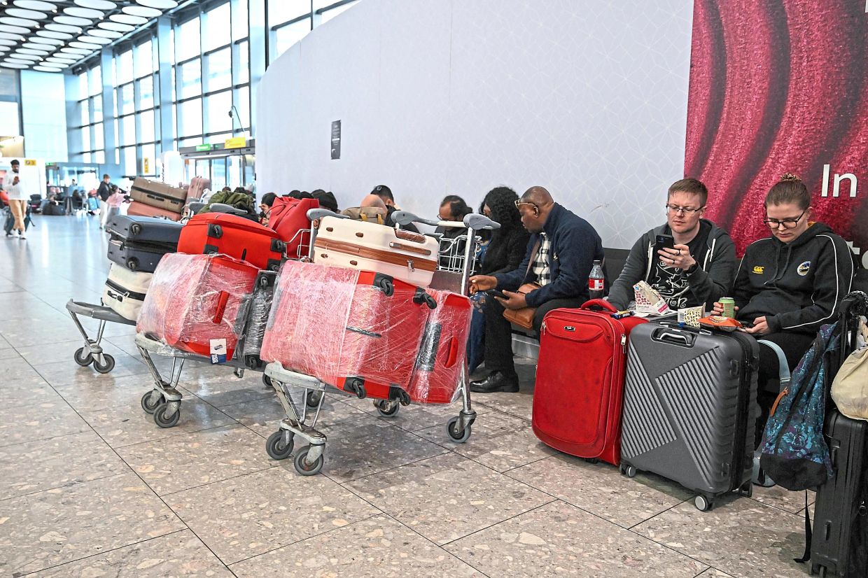 Passengers sit waiting for news about flights at London Heathrow Airport on March 1, when thousands of flights were suddenly cancelled due to the conflict. — AFP
