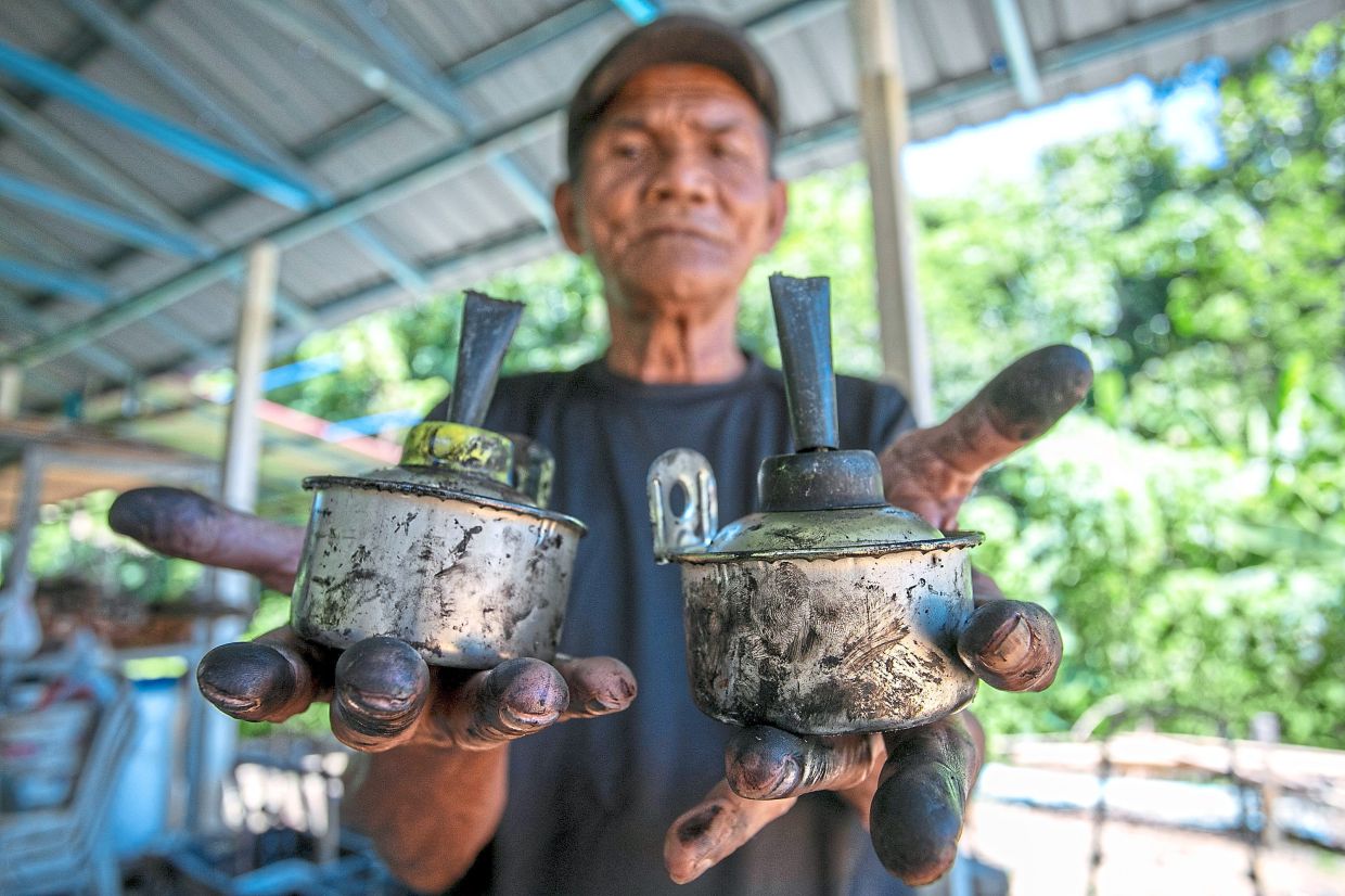 Mansor Ahmad displays a set of oil lamps for the giant mosque–themed structure. Photo: Bernama