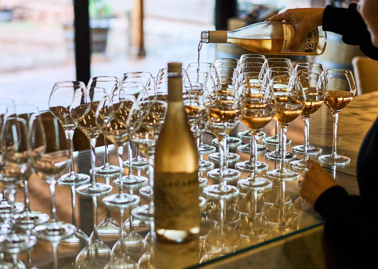 A worker serves white wine to tourists during a tasting at the Lagarde Winery in Mendoza, Argentina, Sunday, March 8, 2026. (AP Photo/Rodrigo Abd)