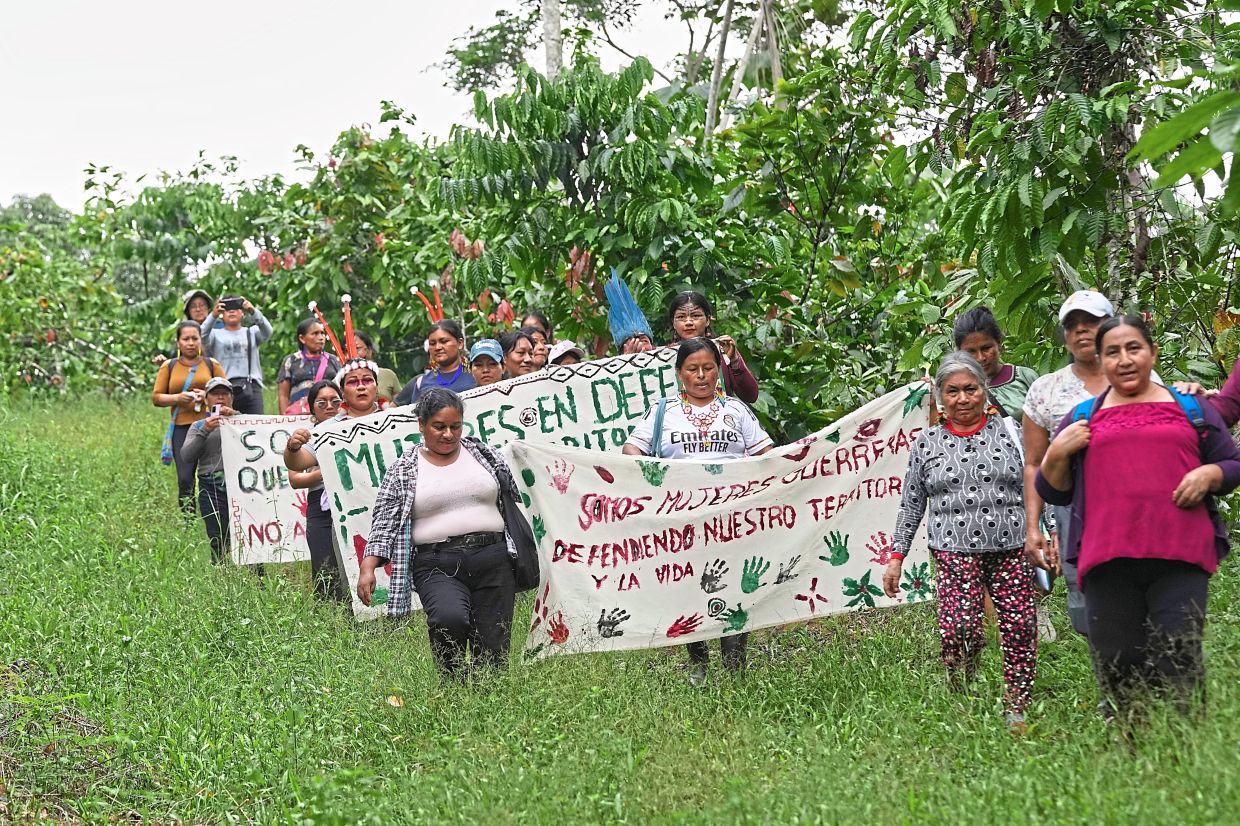 A group of Indigenous women from across Ecuador's Amazon carrying signs during a recent 'toxitour'. 