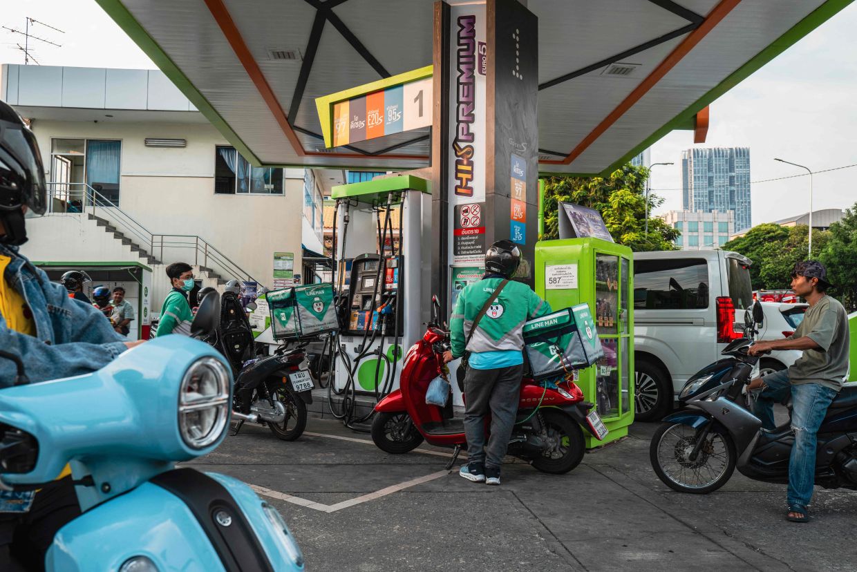 Motorists queue up at a petrol station in Bangkok following import disruptions caused by the Middle East war. Oil prices jumped further above US$100, and Asian stocks mostly fell as the Iran war moved into a third week, with both sides showing no sign of backing down and diplomats trying to ensure safe passage for tankers through the crucial Strait of Hormuz. -- Photo by Anthony WALLACE / AFP