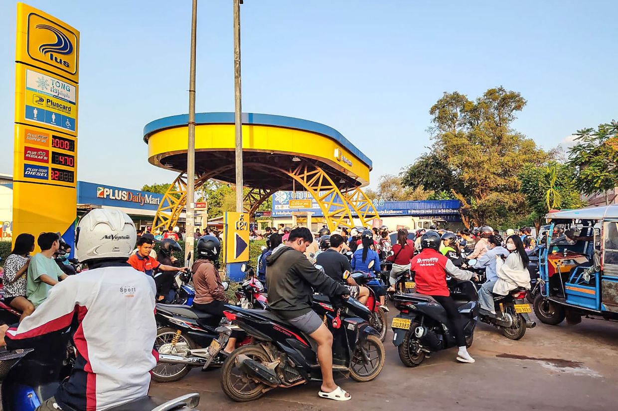 Motorists wait in a queue to refuel their vehicles at a petrol station in Vientiane. Long lines of vehicles queued for hours for fuel in the Laotian capital, Vientiane, as the ripples of the conflict in the Middle East reverberated in landlocked Laos. -- Photo by AFP
