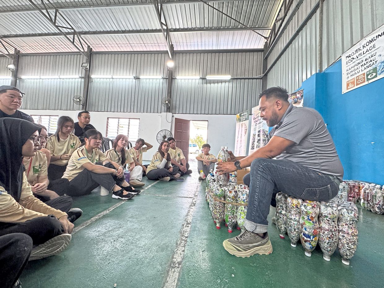 Mohd Faisal, seated on a makeshift ecobrick chair, teaching student volunteers how to make and utilise the upcycle product.