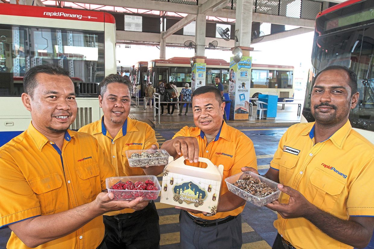 Rapid Penang bus captain Jamil (second from right) sharing some Raya goodies with his colleagues at the bus depot in George Town.