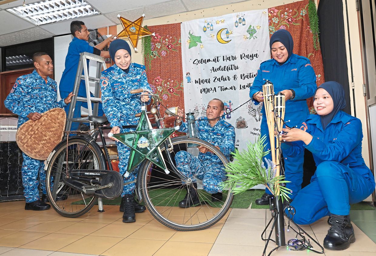 Siti Nabiha and Muhamad Azley (third and fourth from left) helping their colleagues brighten up the APM headquarters in George Town for the coming Raya.