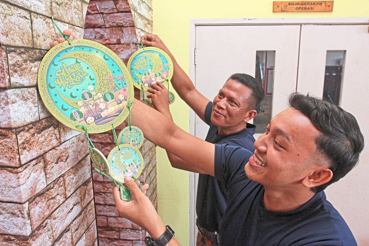 Firemen Alif Najmi Khalid, 26, (right) and Nurul Naimi Ismail, 41, preparing to celebrate Raya by decorating the Kuala Muda Fire Station.