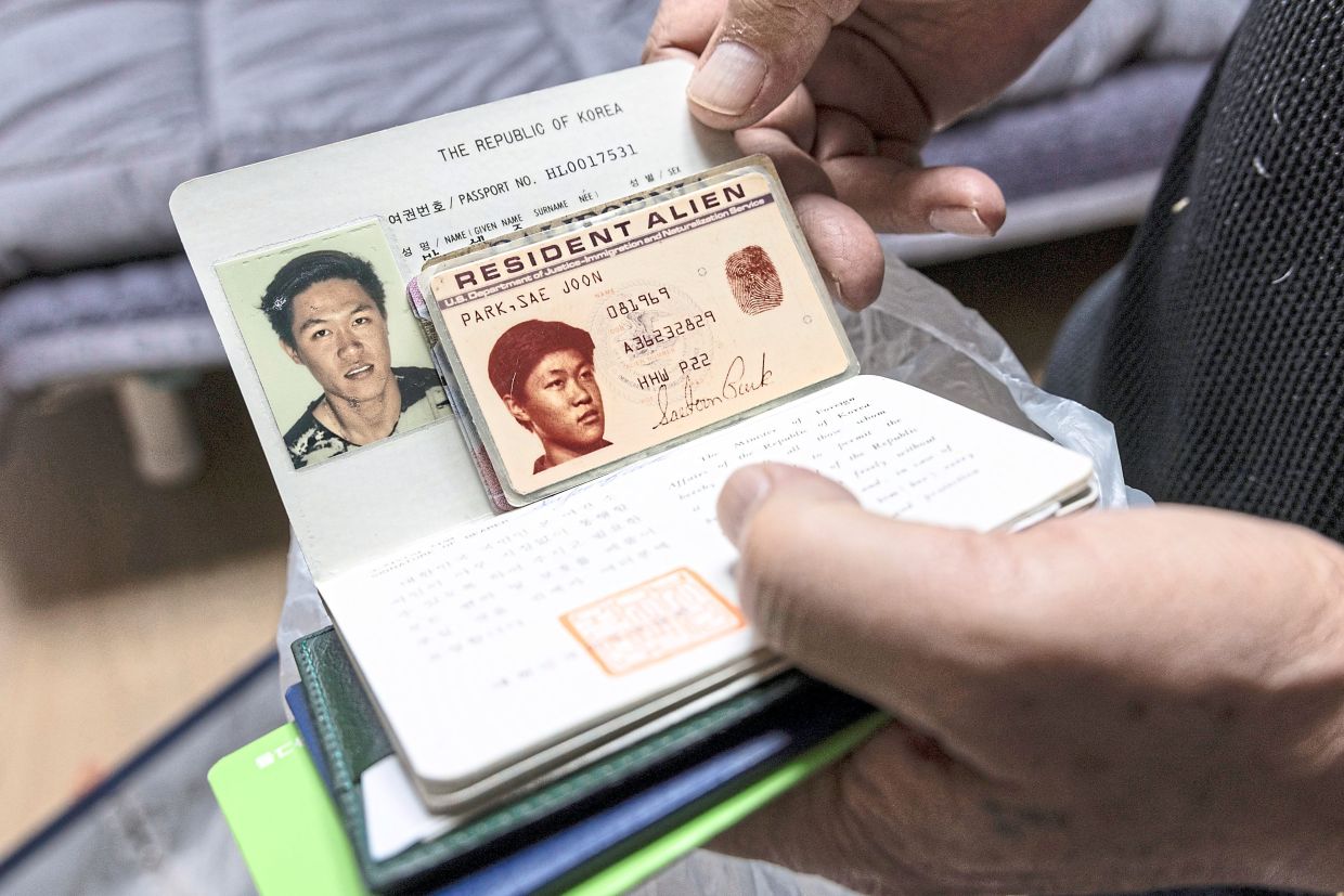 Park displays his old South Korean passport and his US green card at his apartment in Busan.