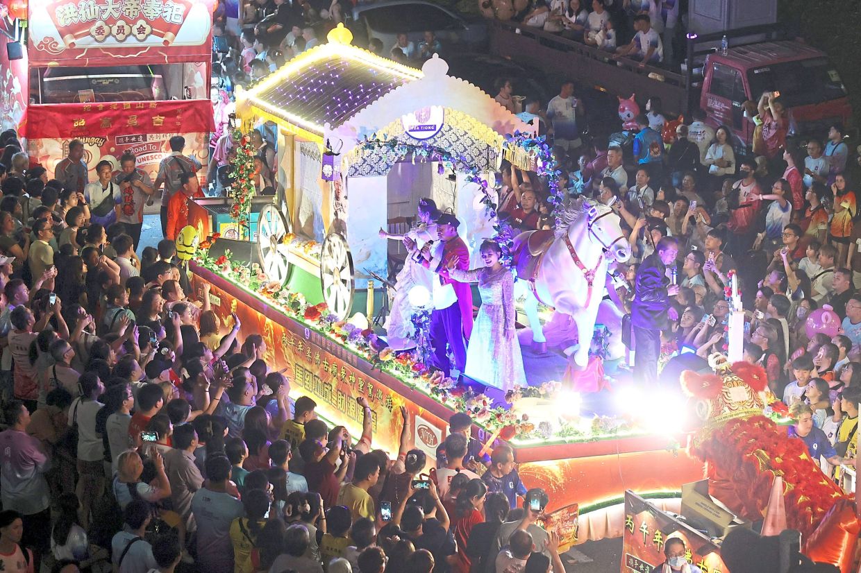 Participants in costumes waving to the crowd from one of the floats.