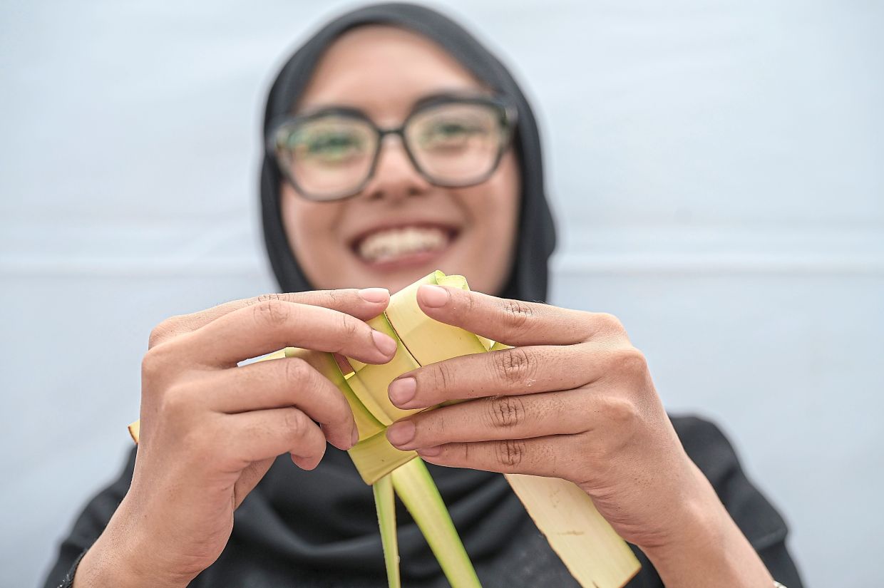 Nur Fatin's interest began at age 10, watching a canteen operator weave coconut leaves into neat ketupat casings. Photo: Bernama