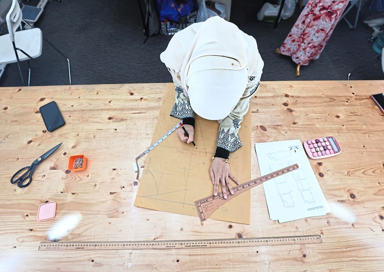 A student works on her clothing pattern – a blueprint used to cut fabrics accurately for a garment. Photo: The Star/Azman Ghani