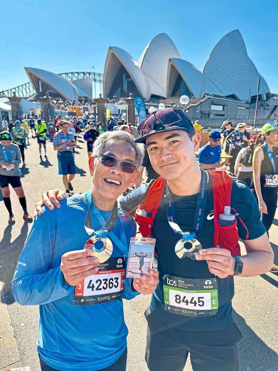 Lim (left) and his son, Kevin, posing with their finishing medal after completing the Sydney Marathon last year.