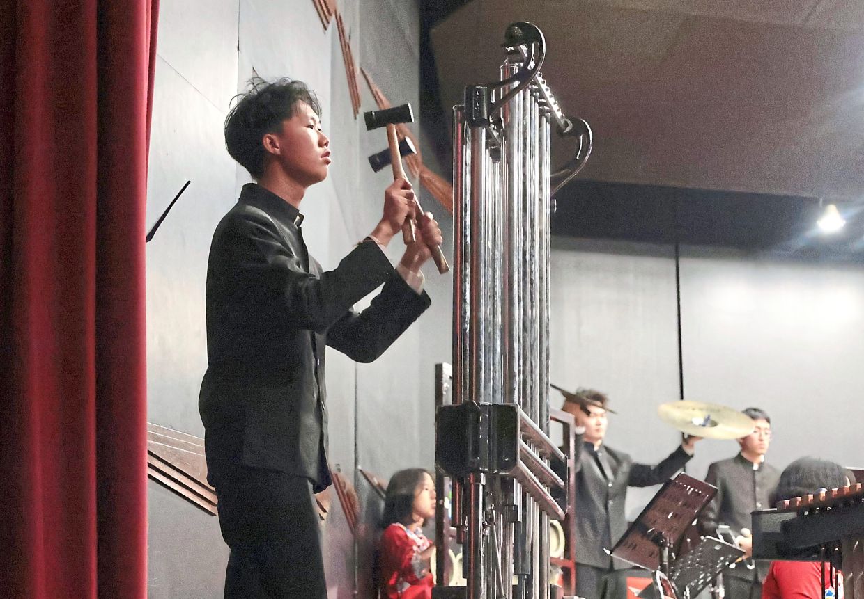 A Chinese orchestra musician striking tubular bells.