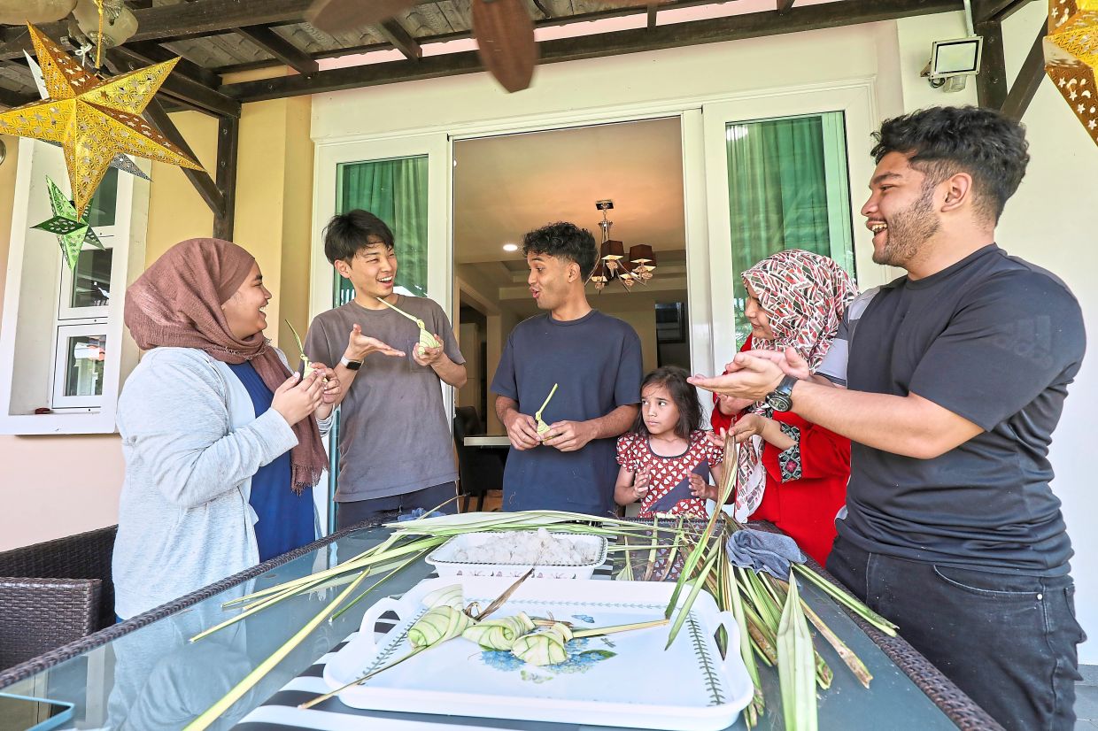 Woven heritage: Amalina Syaza Alyssa (left) demonstrating the traditional method of wrapping ketupat palas to Reo (second, left) as her family members join in the preparations for Ramadan. — YAP CHEE HONG/The Star 