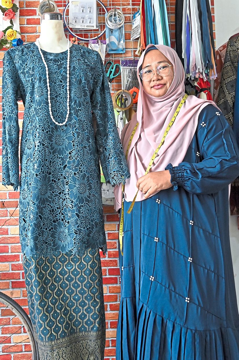 Helmaliza with a ‘baju kurung’ she sewed at her shop in Klebang.