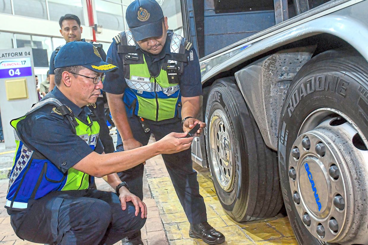 Azrin (left) checking the tyres of a heavy vehicle during the road safety campaign in Shah Alam.